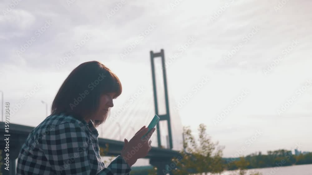 A girl in nature sitting on the ground using a mobile device A girl in nature sitting on the ground using a mobile device