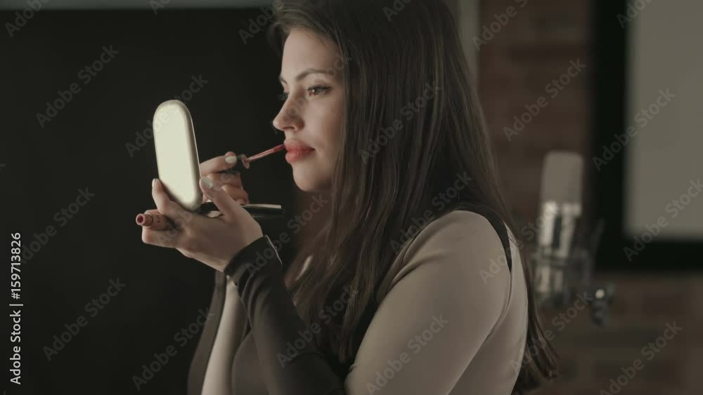 Bautiful young female singer applying lips makeup with cosmetic brush Bautiful young female singer applying lips makeup with cosmetic brush