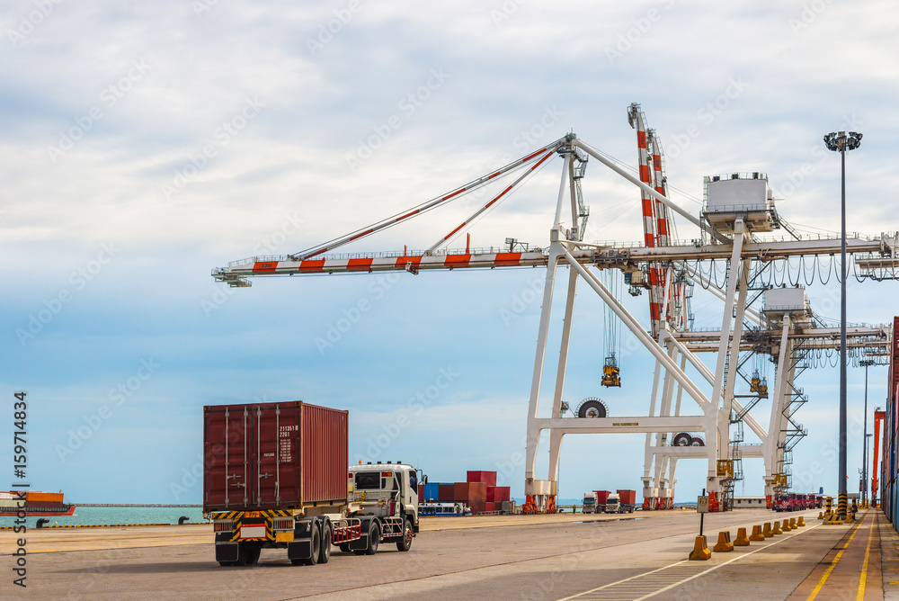 Industrial crane and lorry truck loading containers in cargo freight ship container seaport during import and export transportation