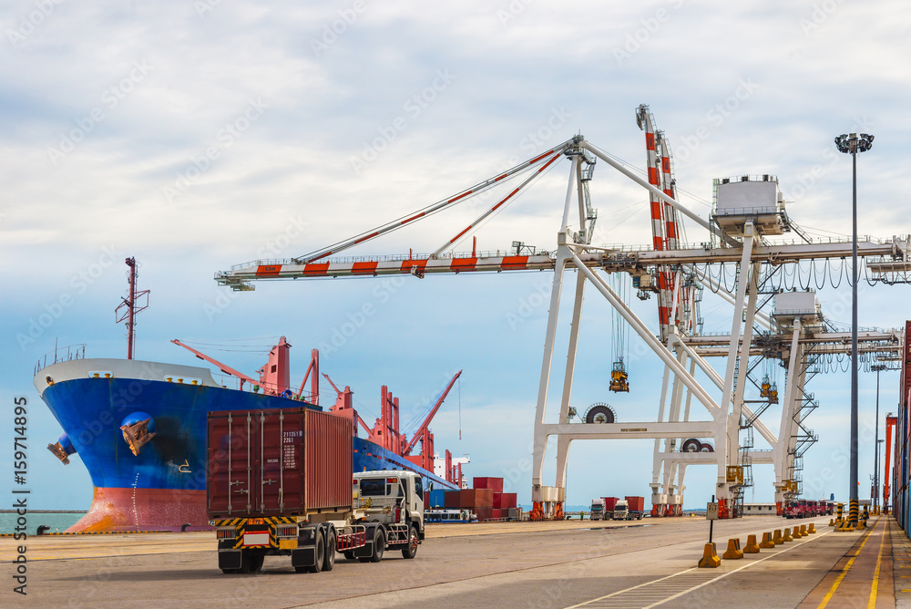 Industrial crane and lorry truck loading containers in cargo freight ship container seaport during import and export transportation