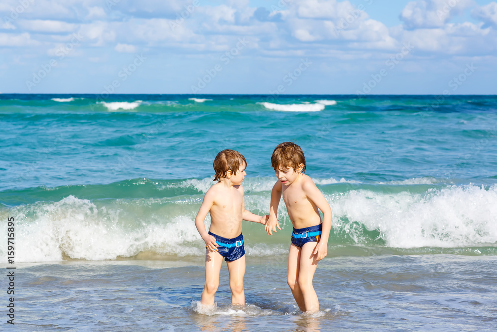 Two kid boys running on ocean beach in Florida