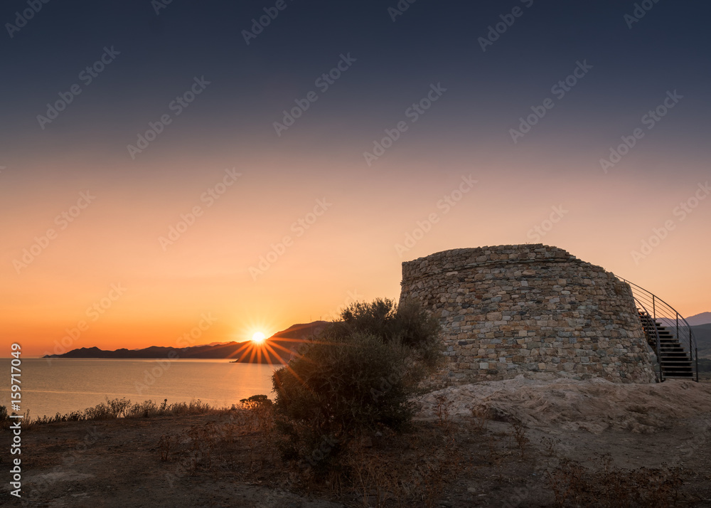 Sun rising behind Genoese tower at Lozari in Corsica