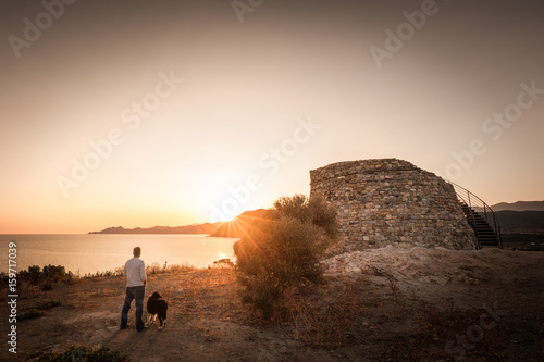 Man & dog watching Sunrise behind Genoese tower in Corsica