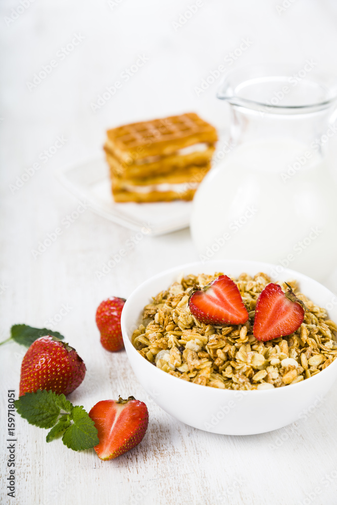Granola with strawberry and a jug of milk Granola with strawberry and a jug of milk