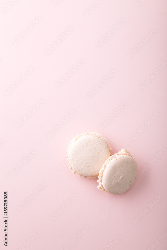 Pair of cream macaroons on pink background. Vertical composition with copy space.