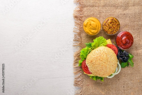 Hamburger with cheese, meat and green onions on Wooden background. Top view. Free space.