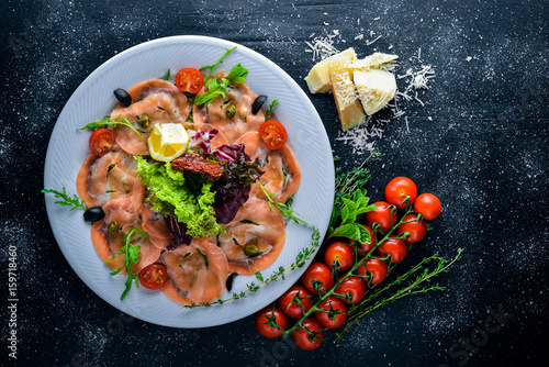 Carpaccio of fish, vegetables, cheese, spices, to Wooden background. Top view. Free space.