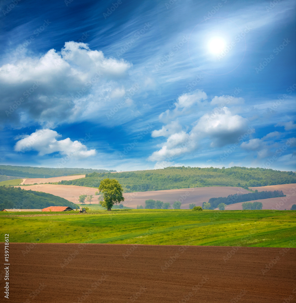Country dry plowed earth agricultural green farmland on blue sky Country dry plowed earth agricultural green farmland on blue sky