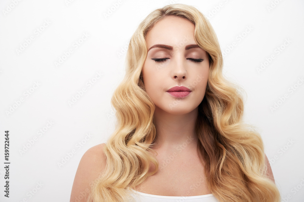 Portrait of beautiful young woman with wavy blond hair and eyes closed standing against white background Portrait of beautiful young woman with wavy blond hair and eyes closed standing against white background