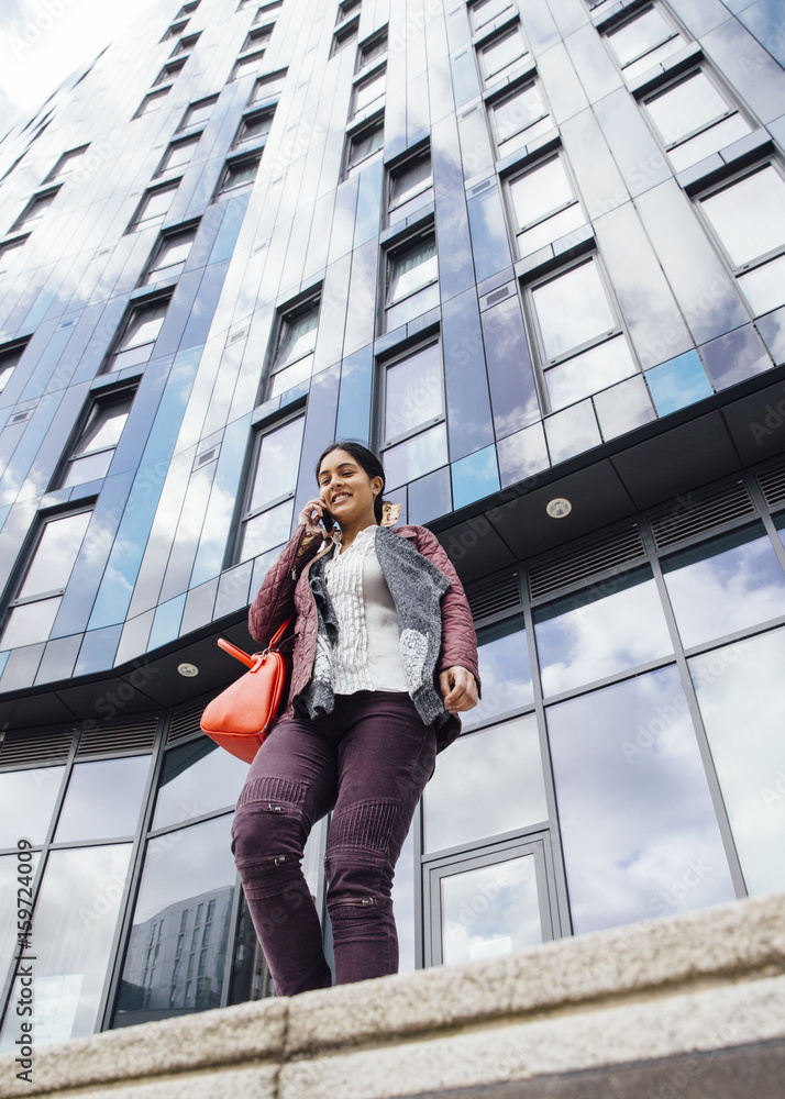 Businesswoman is leaving work while talking to someone on her mobile phone. Businesswoman is leaving work while talking to someone on her mobile phone.