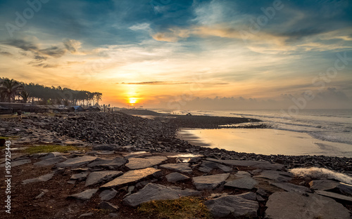 Moody sunset sky over seascape with beach rocks and boulders. © Roop Dey