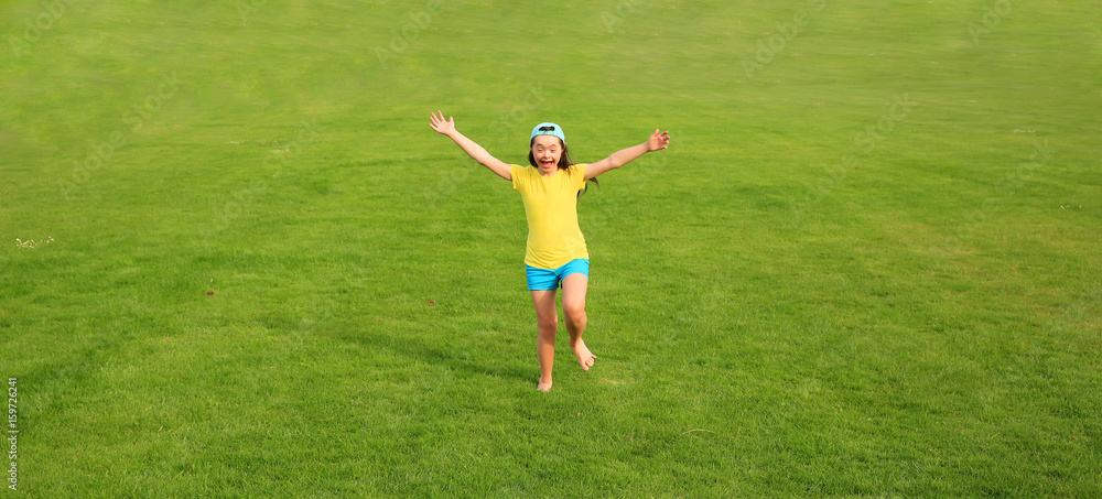 Young girl run on the background of green grass