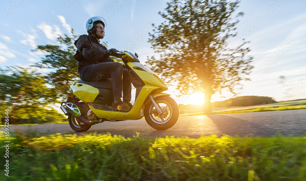 Fototapeta premium Motocyklista jedzie na pustej drodze z zachodem słońca niebo