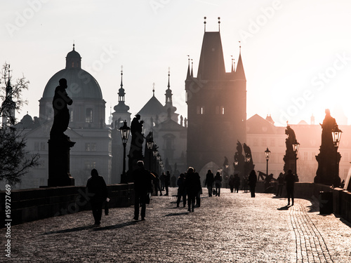 Foggy morning on Charles Bridge, Prague, Czech Republic. Sunrise with silhouettes of walking people, statues and Old Town towers. Romantic travel destionation.