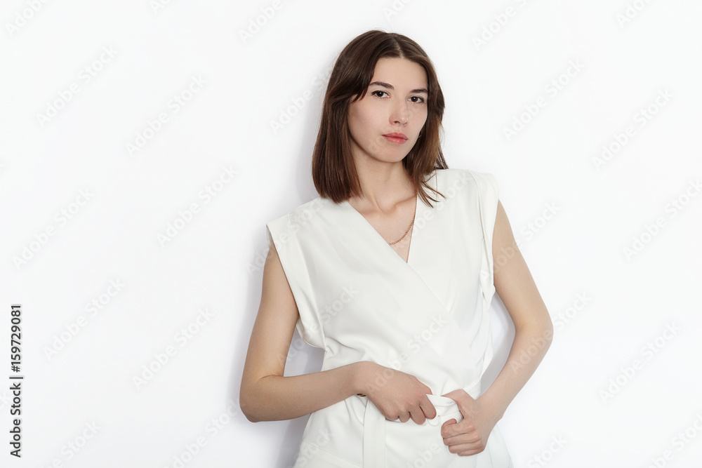 Young beautiful brunette beginner model woman in white blouse practicing posing showing emotions on white wall studio background Young beautiful brunette beginner model woman in white blouse practicing posing showing emotions on white wall studio background