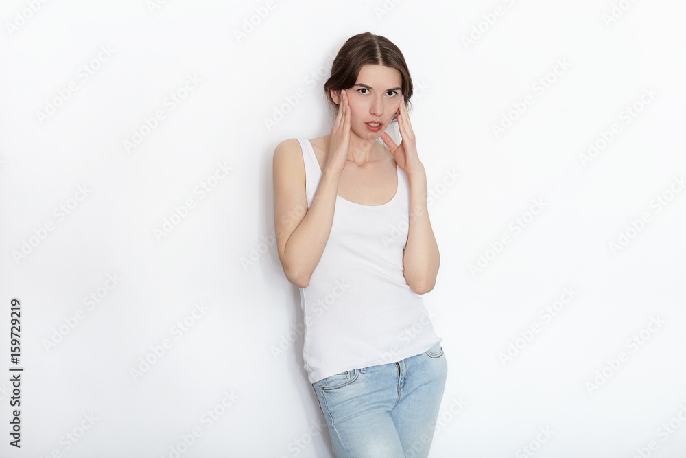 Young beautiful brunette beginner model woman in white t-shirt blue jeans practicing posing showing emotions on white wall studio background Young beautiful brunette beginner model woman in white t-shirt blue jeans practicing posing showing emotions on white wall studio background