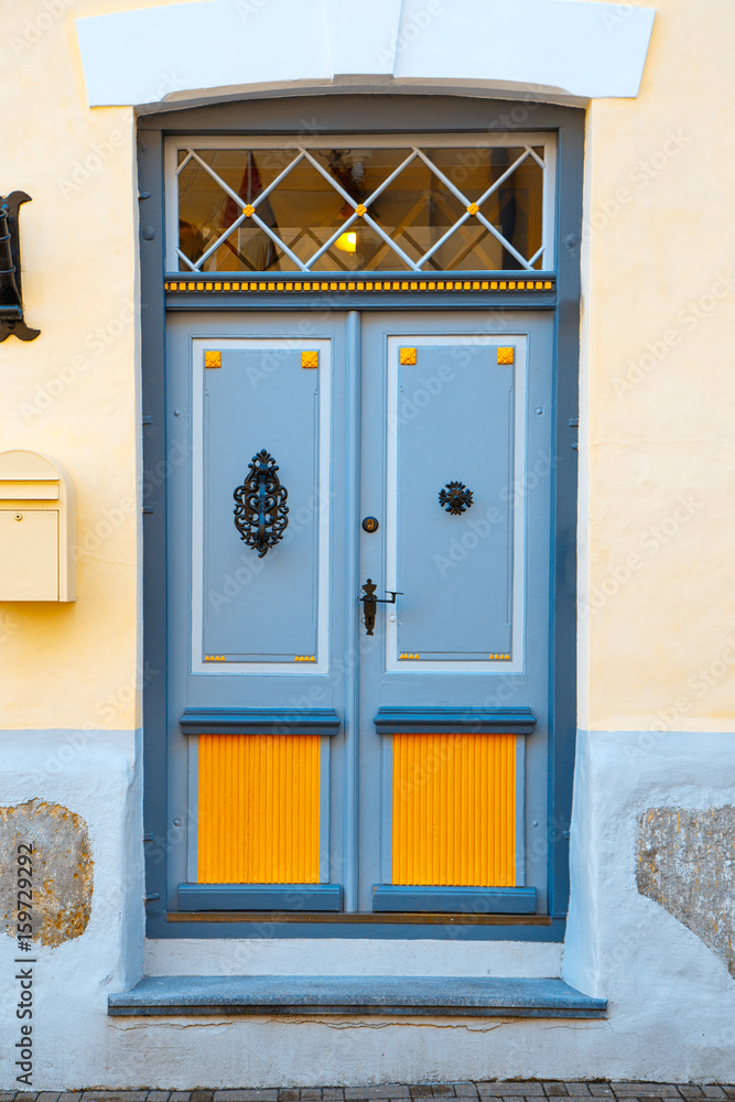 Fototapeta premium A beautiful vintage blue door with orange inserts with an old handle and a lock. The same doors you can find in historical centers of many european cities.