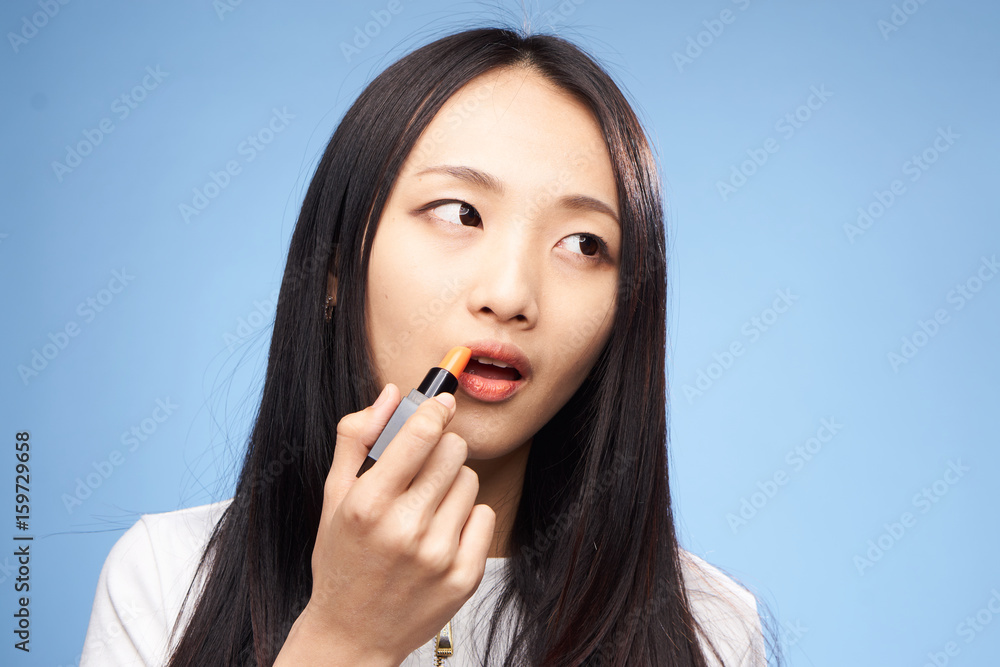 Woman is painting lipstick on a blue background portrait Woman is painting lipstick on a blue background portrait