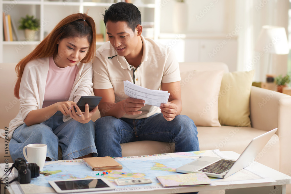 Portrait of young modern couple planning finances for summer vacation Portrait of young modern couple planning finances for summer vacation