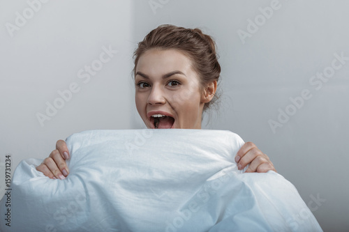 Photography Close-up portrait of young smiling woman covering face with bedcover in bed