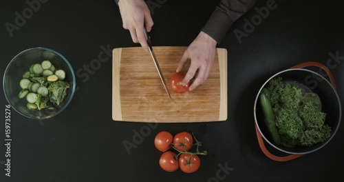 Cutting tomatoes for dishes on the table. Vegetables during the cooking process dishes. Vegetables for healthy eating and dieting. Top view. photo