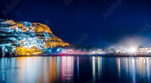 Matala beach with caves on the rocks that were used as a roman cemetery and at the decade of 70's were living hippies from all over the world, Crete, Greece. Rock festival at night. © gatsi