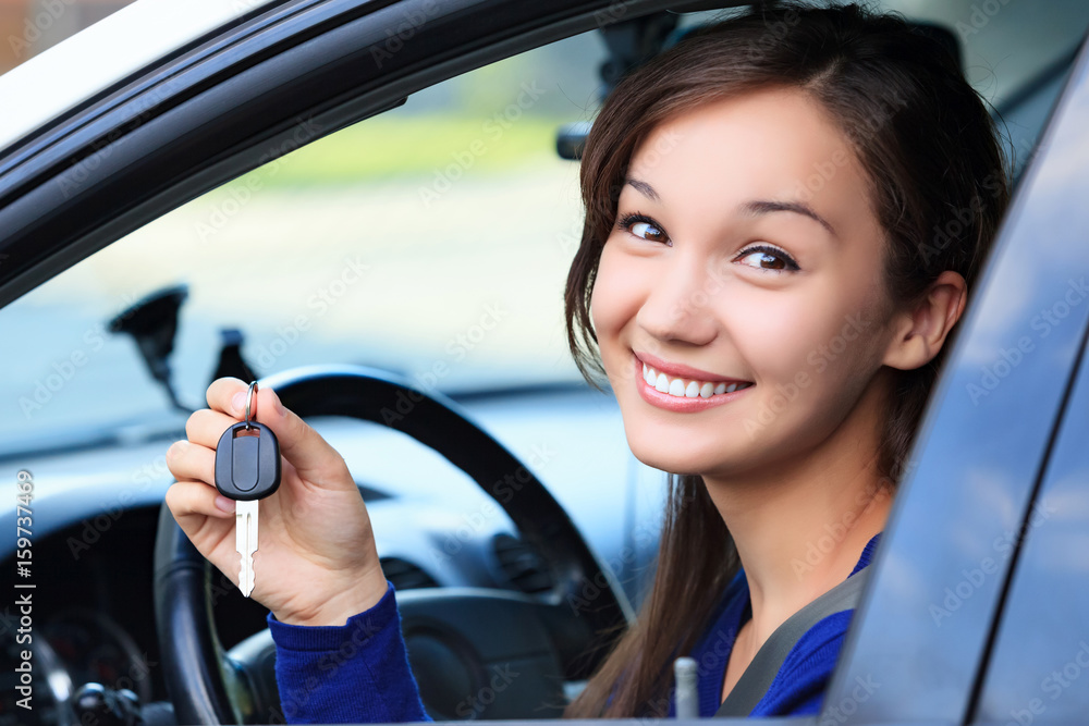 Beautiful young smiling happy girl shows the car key in her hand Beautiful young smiling happy girl shows the car key in her hand