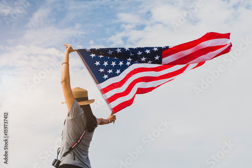 Obraz na plátně Young asian woman holding American flag on blue sky background