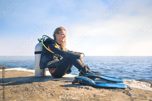 Scuba diver sitting on a pier at the suset