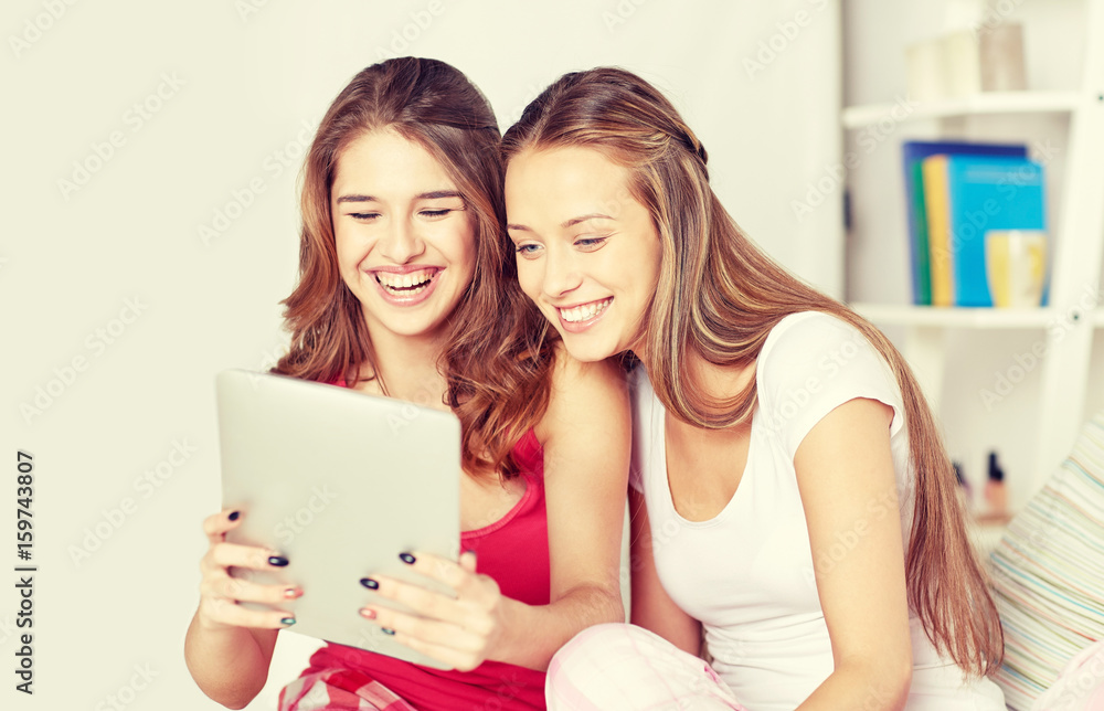 happy friends or teen girls with tablet pc at home
