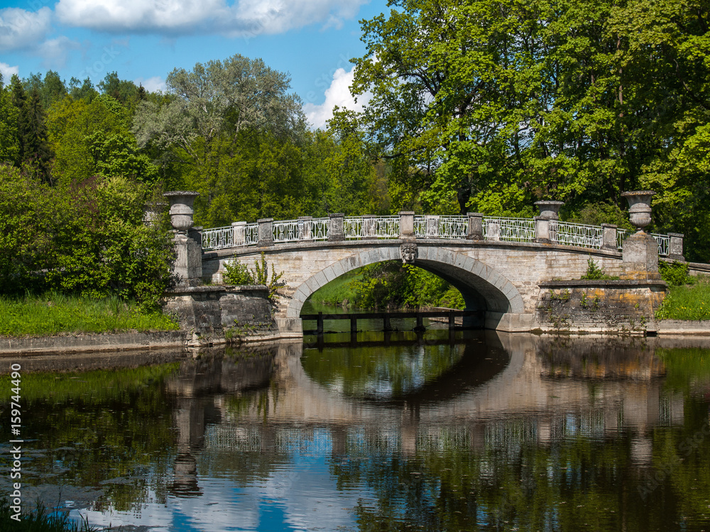 Stone bridge on the lake in the park in summer