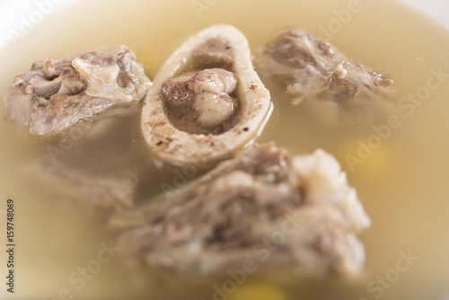 Bone marrow soup, served in a white bowl, light background, isolated