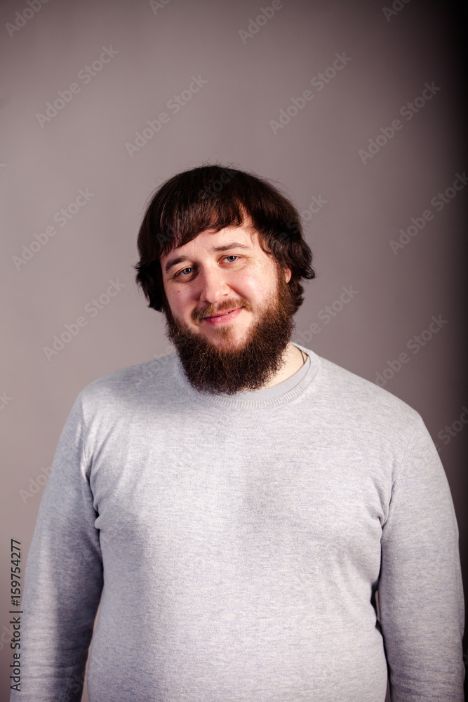 Obraz premium confident, lucky man with beard in front of grey background