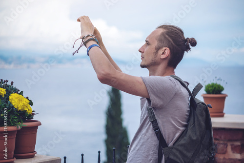 Man traveler with backpack makes a photo on your smartphone outdoors with mountains in the background photo