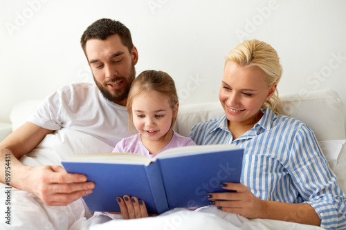 happy family reading book in bed at home