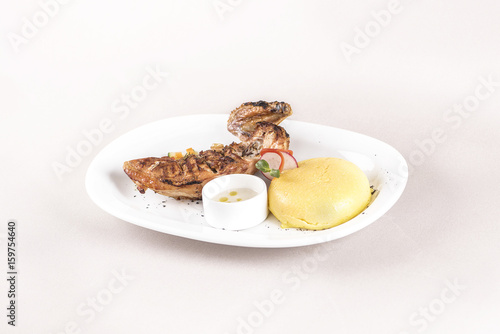 Chicken half breast and wing with polenta and garlic sauce “mujdei”, decorated with fresh leafs, light background, isolated photo