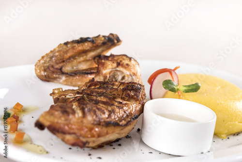 Chicken half breast and wing with polenta and garlic sauce “mujdei”, decorated with fresh leafs, light background, isolated photo