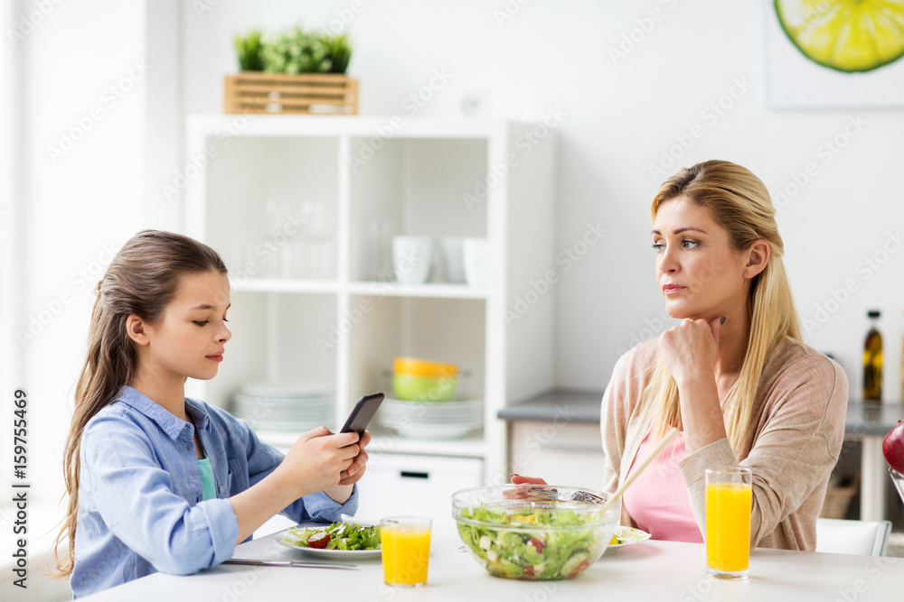 sad woman looking at her daughter with smartphone
