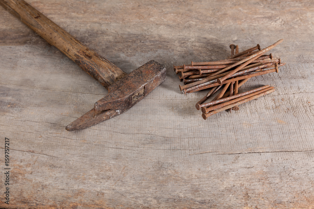 old and rusty claw hammer and nails on a wooden workbench old and rusty claw hammer and nails on a wooden workbench