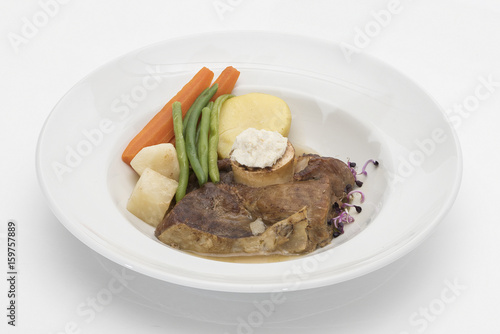 Baked beef marrow with vegetables, decorated with purple leafs, placed on white plate, light background, isolated