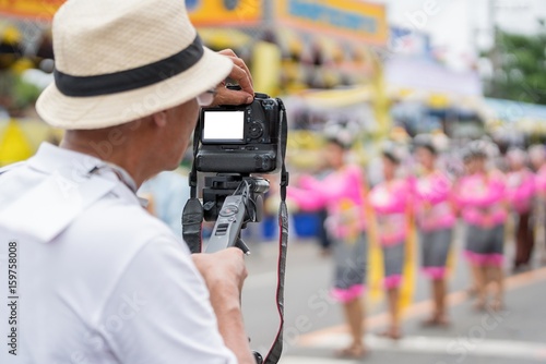 Video camera operator working with his professional equipment in hand at parade festival.