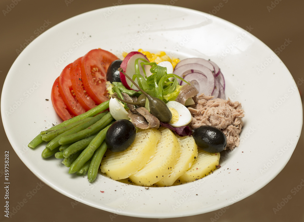 Tuna salad with vegetables, placed on a white plate, brown background Tuna salad with vegetables, placed on a white plate, brown background