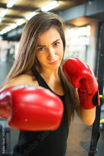 Sporty woman with red boxing gloves punching towards camera. © Bojan