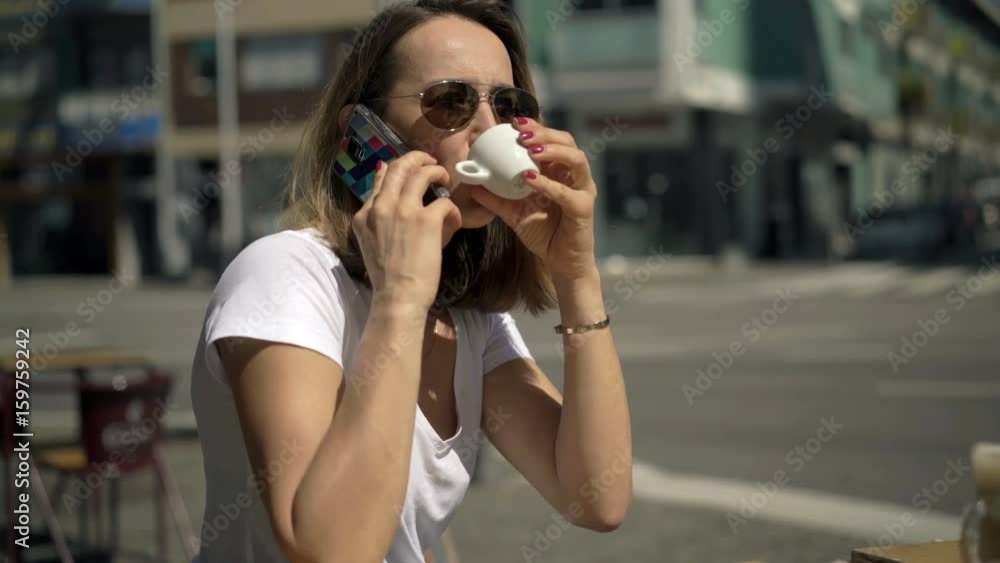 Young woman drinking espresso and talking on cellphone in cafe in city
Young woman drinking espresso and talking on cellphone in cafe in city
