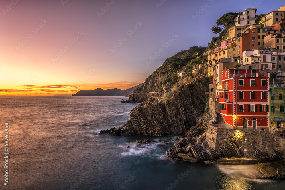 Riomaggiore fisherman village at sunset. Riomaggiore is one of five famous colorful villages of Cinque Terre in Italy, suspended between sea and land on sheer cliffs.