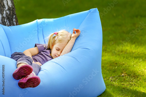 Young cute blond girl sleeping on an inflatable bed outdoors photo