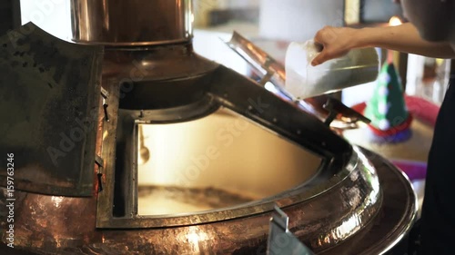 Close up of a young brewery worker s hands opening a lid and adding some malt. Handheld real time close up shot