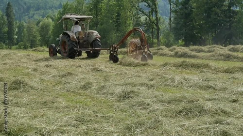 Traktor beim Heu wenden auf dem Feld photo