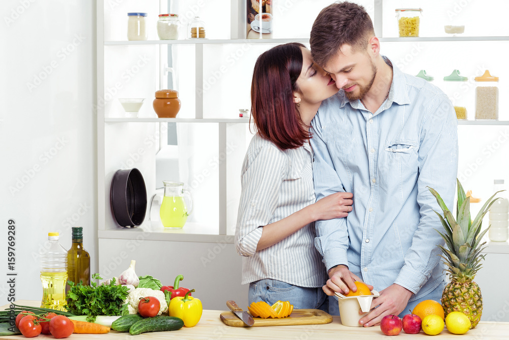 happy couple in love in kitchen making healthy juice from fresh orange. couple is kissing happy couple in love in kitchen making healthy juice from fresh orange. couple is kissing