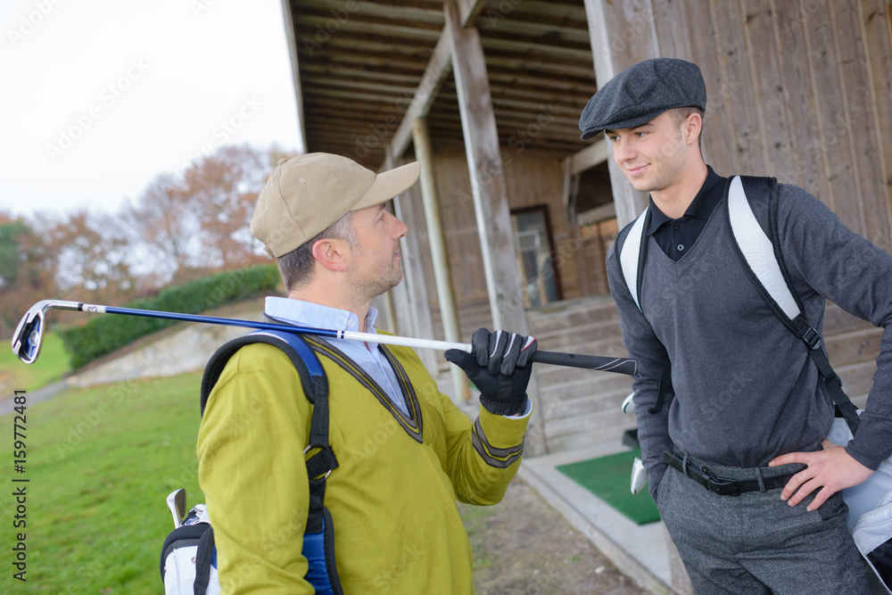 golfing friends talking while holding clubs at the golf course golfing friends talking while holding clubs at the golf course